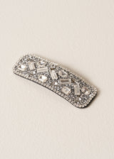 Decorative silver hairclip with gemstones on a beige background