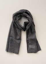 Black and white dot print cotton scarf made from breathable, lightweight fabric, on a beige background