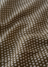Close-up of fabric with a subtle pattern on a brown background
