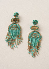 A pair of beaded tassel earrings featuring turquoise and gold seed beads in a semi-circular arch pattern with dangling fringe, displayed on a textured off-white background.