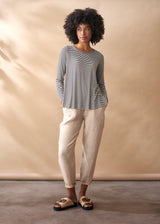 Woman wearing a striped shirt and beige pants against a beige background