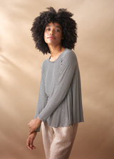 Woman wearing a striped long-sleeve top against a beige background