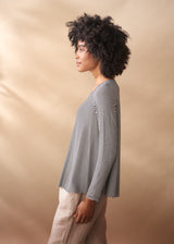 Woman wearing a striped shirt and light pants against a beige background