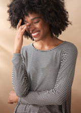 Woman wearing a black and white striped long-sleeve top against a beige background
