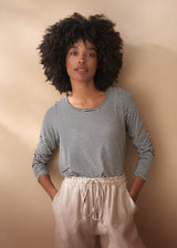 Woman wearing a striped shirt and beige pants against a beige wall