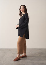 Woman wearing a black cotton oversized blouse and brown linen trousers
