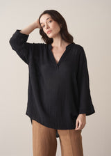 Woman wearing a black cotton oversized blouse and brown linen trousers