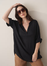Woman wearing a black cotton oversized blouse and brown linen trousers