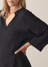 Woman wearing black crinkled cotton a-line top with beige linen trousers