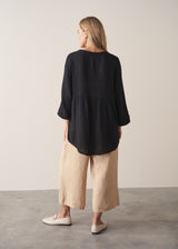 Woman wearing black crinkled cotton a-line top with beige linen trousers