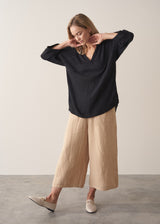 Woman wearing black crinkled cotton a-line top with beige linen trousers