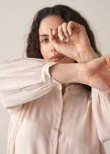 Woman wearing blush pink pinstripe blouse with puff sleeves