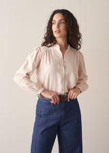 Woman wearing blush pink pinstripe blouse with puff sleeves