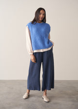 Woman wearing a light pink blouse with pinstripes and long sleeves with dark navy trousers