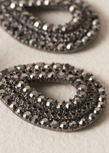 Close up of a pair of Ainsley Earrings featuring a striking teardrop silhouette embellished with jet-black crystals
