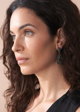 A model wearing the Ainsley Earrings featuring a striking teardrop silhouette embellished with jet-black crystals