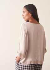 Woman wearing pearlescent light lilac satin top with navy check trousers and a dark plum chunky cardigan