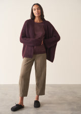 A woman wearing a plum satin top with khaki green trousers
