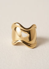 Gold chunky wave ring on a light beige background