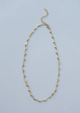A gold necklace with heart-shaped charms, on blue background