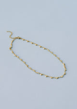 A gold chain link necklace with heart-shaped charms, on a blue background