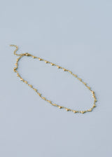 A gold chain link necklace with heart-shaped charms, on a blue background