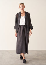 Woman wearing semi-sheer button up black shirt with dark grey wide leg trousers.