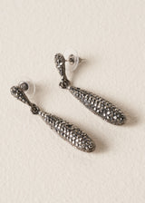 Sparkly silver crystal adorned tear drop earrings on a beige background