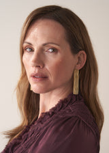 Woman wearing gold chain tassel earrings and beige background