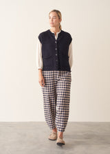 Woman wearing dark blue chunk knit waistcoat with white shirt and blue checked trousers