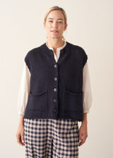Woman wearing dark blue chunk knit waistcoat with white shirt and blue checked trousers
