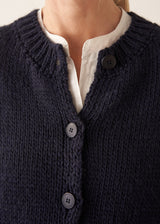Woman wearing dark blue chunk knit waistcoat with white shirt and blue checked trousers