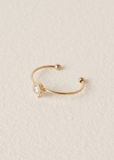 Dainty gold everyday ring with crystal on beige background