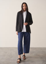 Woman wearing black oversized floppy jacket with a white shirt and blue jeans.