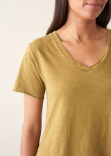 A woman wearing a olive green v-neck t-shirt with grey charcoal stripe trousers and sandals