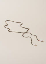 Beaded black drop necklace with freshwater pearl detail, on a beige background