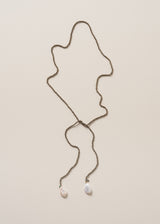 A beaded drop necklace with black beads and freshwater pearl detail on beige background