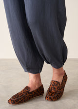 A woman wearing dark blue balloon leg trousers with pleat details and a white cotton shirt.
