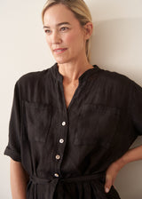 Woman wearing a short sleeve black linen jumpsuit with a button up front and waist tie