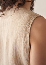 Woman wearing a beige striped linen waistcoat with a white vest top and striped linen trousers