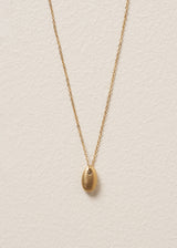 Gold minimal necklace with a simple oval pendant on a beige background