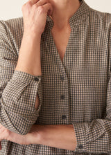 Woman wearing a midi length long sleeve checked dress with button up front.