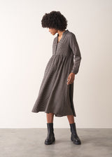 Woman wearing a checked midi dress and chunky boots against a plain background