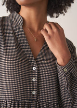 Woman wearing a checked midi dress and chunky boots against a plain background