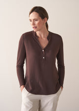 Woman wearing a brown long-sleeve jersey top against a plain background
