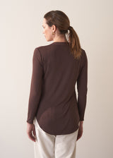 Woman wearing a brown long-sleeve jersey top against a plain background
