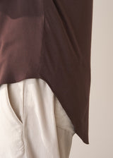 Woman wearing a brown long-sleeve jersey top against a plain background