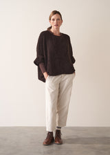 Woman wearing a brown long-sleeve jersey top against a plain background