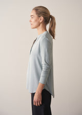 Woman wearing long sleeve pale blue top with black wide leg trousers