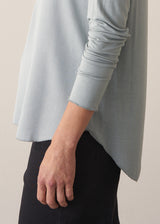 Woman wearing long sleeve pale blue top with black wide leg trousers